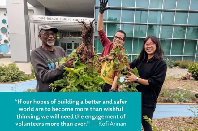 A diverse group of volunteers standing in front of the Long Beach Public Library holding a bunch of weeds.