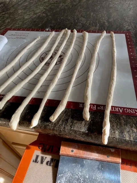 multiple pieces of dough shaped like into ropes