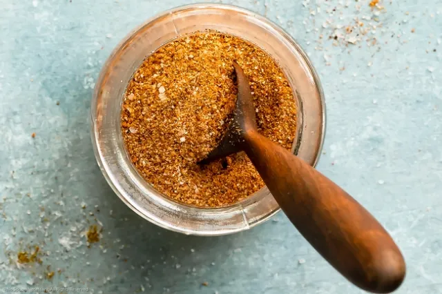 A bowl of seasoning with a wooden spoon.