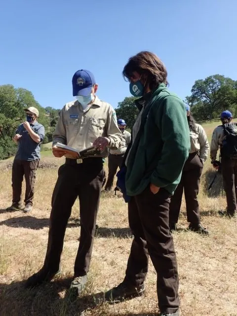 Two California Naturalist students reading a book outside