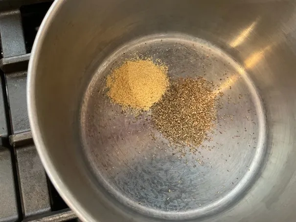 Ground spices toasting in a pan.