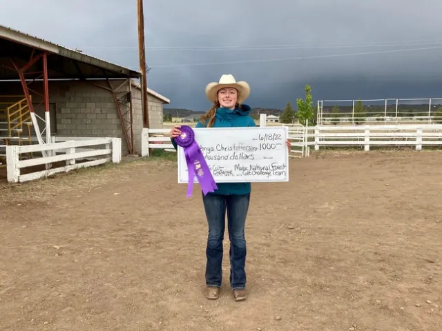 Goldie shown smiling holding a poster-size $1,000 check.