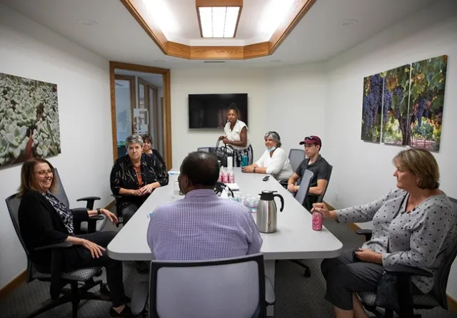 Eight people sit around a conference table.