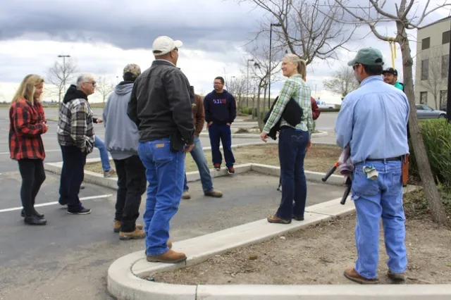 Reid speaks as people wearing jackets and one holding a pair of pruning shears encircle her.