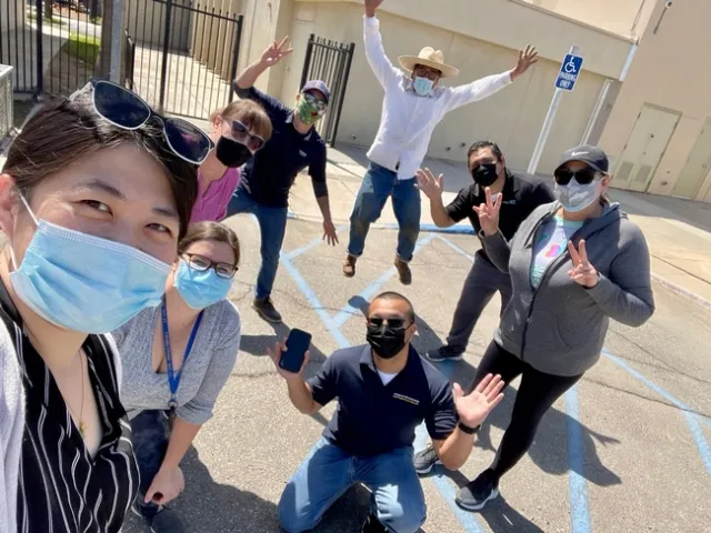 The team members, wearing face masks, pose on a school playground.