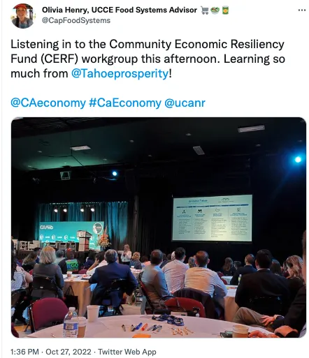 People sitting around round tables look at speaker and PowerPoint slide.