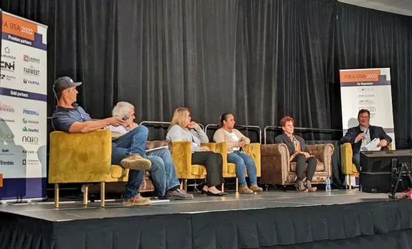 Panelists sit in armchairs on stage.