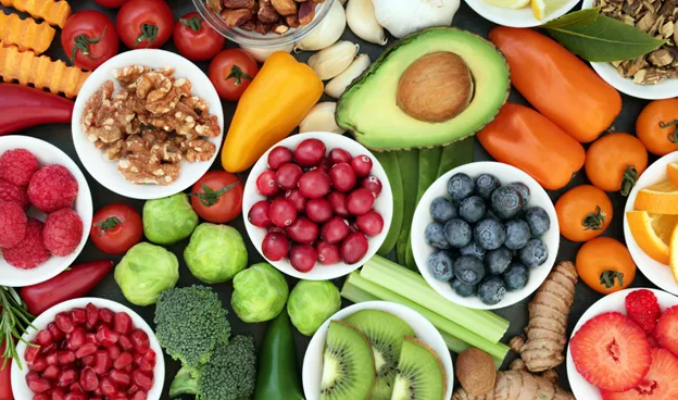 variety of colorful foods including peppers, blueberries, cut strawberries, ginger, and avocado