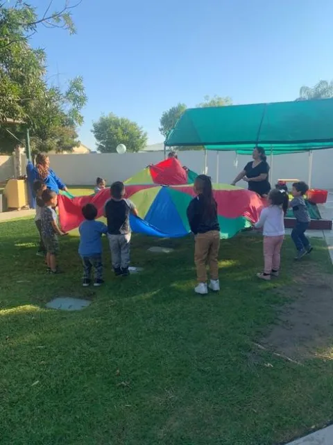 Students stand in a circle and hold a colorful parachute