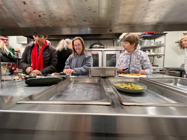 Three ladies chop vegetables in a kitchen.