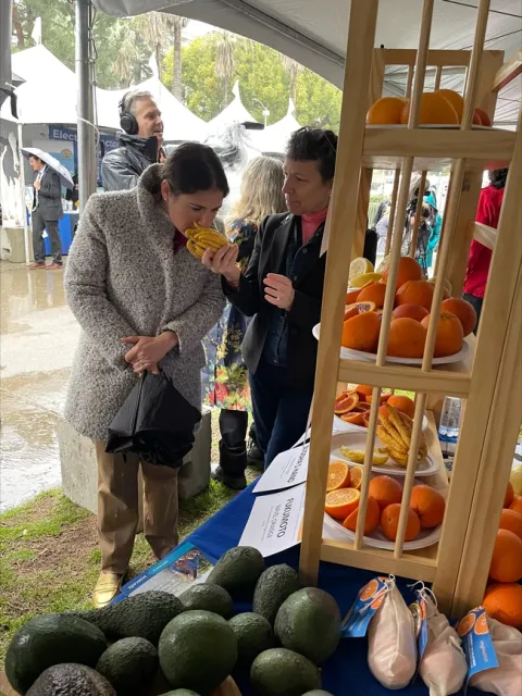 Deanne Meyer invites Assemblymember Rebecca Bauer-Kahan to sniff the aromatic buddha's hand.