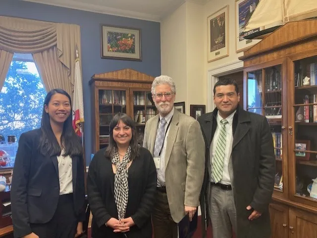 The four people stand together in a congressional office.