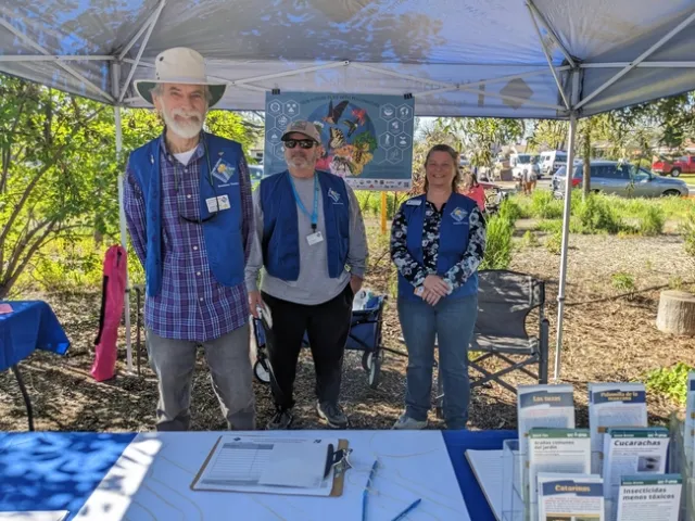 Three smiling people behind a table.