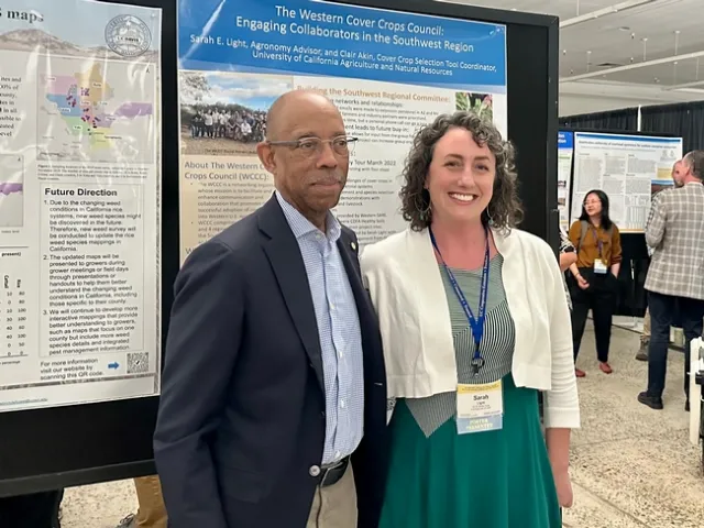 Drake and Light pose in front of her poster on cover crop research.