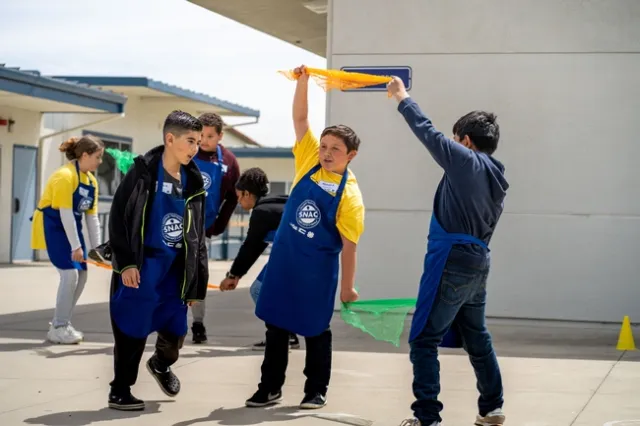 Three youth, outside on a play ground with scarves