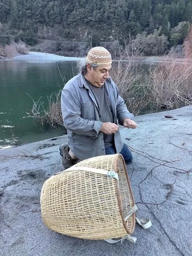 The Klamath River and trees are in background as Hillman harvests willow roots