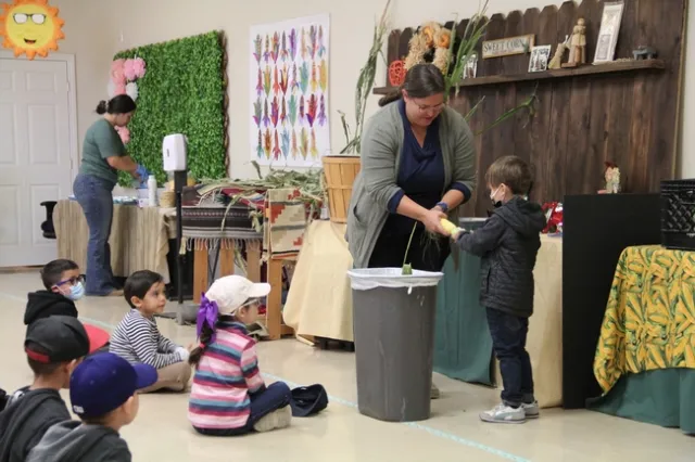 Pies de grabado Stacey Amparano ayuda a sus jóvenes voluntarios a desgranar una mazorca.
