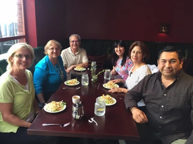 A group of adults sitting at a dining table with salads in front of them.