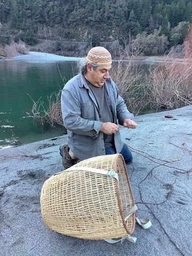 Leaf Hillman, líder ceremonial Karuk, practicante cultural y colaborador del proyecto, cosecha raíces de sauce junto a un canasto Karuk en Tishànik cerca del rio Klamath.