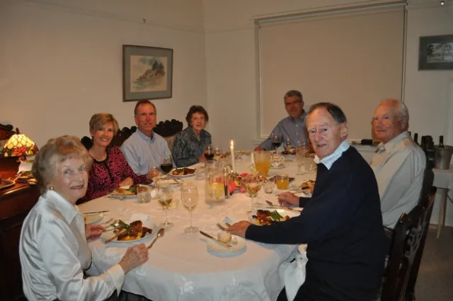 Seven people sit around a dining table.