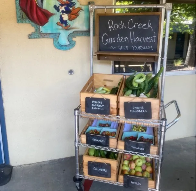 A cart full of fresh produce outside of a classroom.