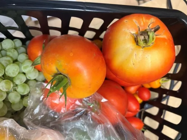 A grouping of tomatoes and grapes in a basket.