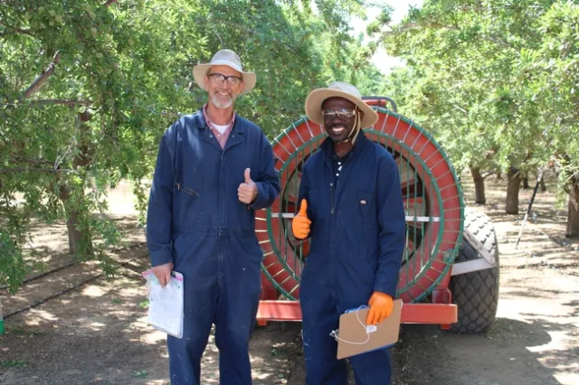 UCCE farm advisor Dr. Franz Niederholzer and UCCE specialist Dr. Peter Larbi pose behind an airblast sprayer in Arbuckle, CA