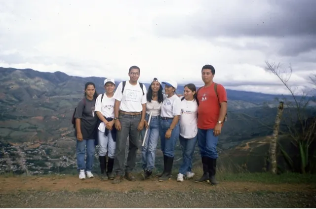 An instructor and students stand on top of mountain.