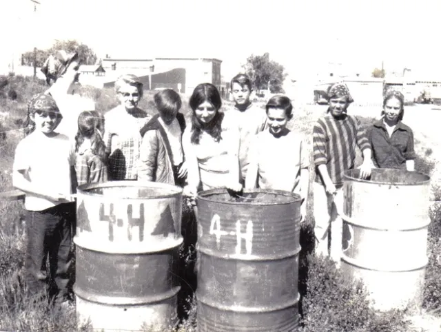 A black-and-white photo showing kids posing with painted trash cans