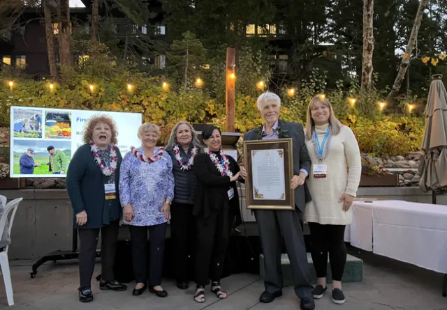 Group of five people, shoulder to shoulder with one person holding a framed resolution.