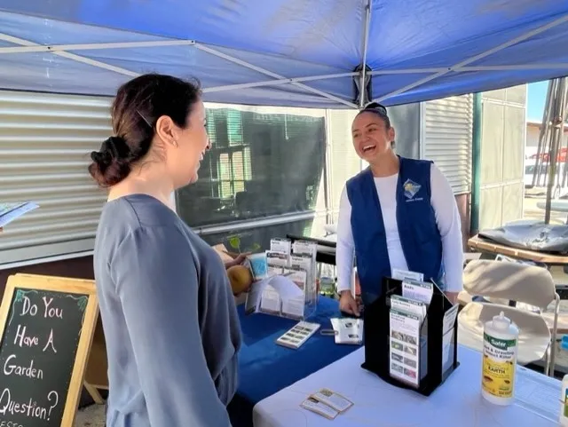 Smiling woman wearing blue vest talking to the public.
