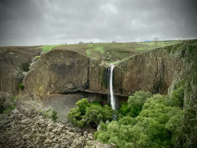 A waterfall spills over a rocky cliff in the Sierra Nevada.