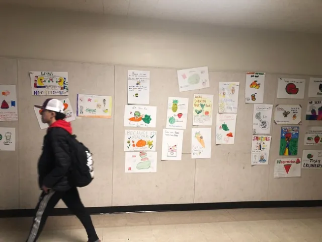 During passing period, a Hillview student walks by the collage of fruit and veggie posters created byEatFit students to promote the healthy choice school-wide.