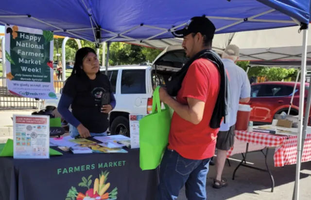 A young woman speaks with a man holding a lime green shopping bag