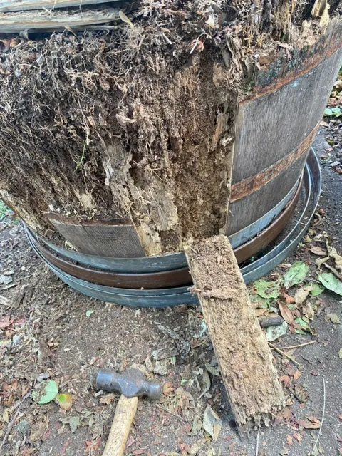 Close up of half wine barrel used as a planter being taken apart.