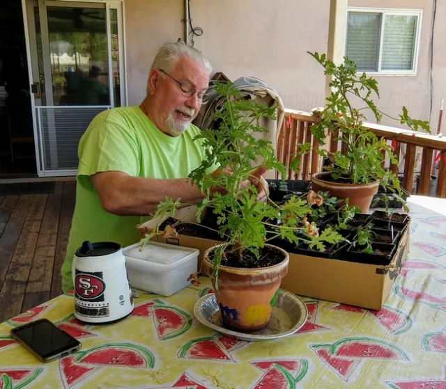 Author sitting outside on a bench with seedlings.