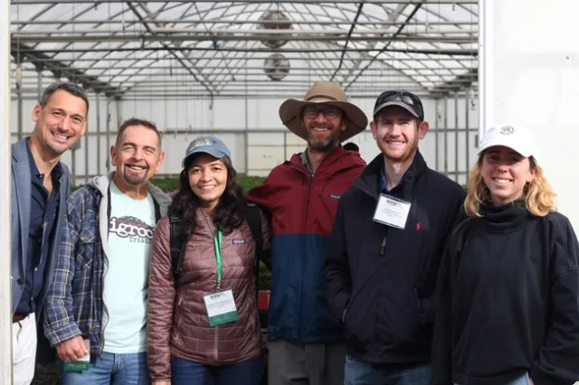A group of six individuals, 4 men and 2 women, smiling at the camera.