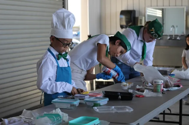 Three youth decorate cupcakes.