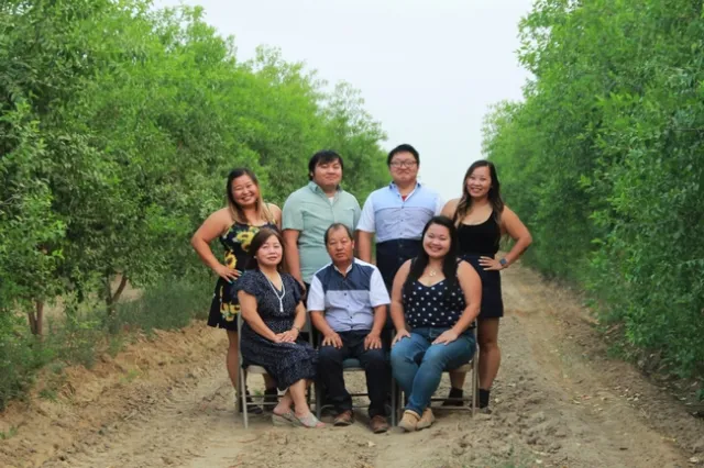Lilian's siblings stand behind her and her parents, who are sitting in chairs in between rows of jujube trees