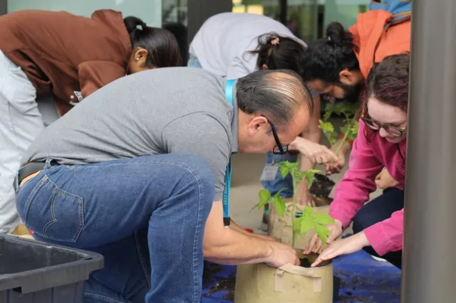 A man hunches down to assist a young lady with planting.