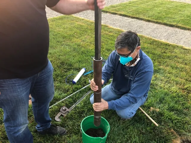 A man digs a hole to install a tube into it.