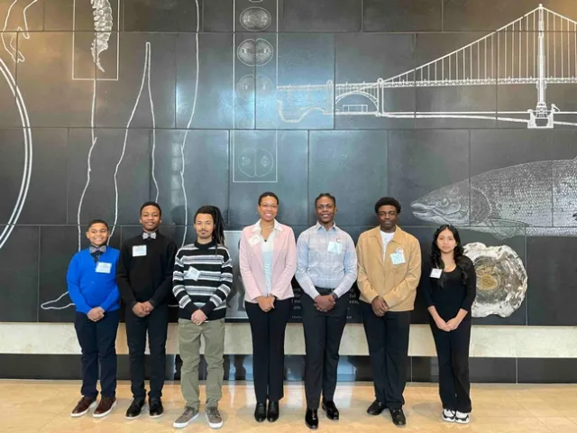6 youth standing with Eve in front of black background wall mural