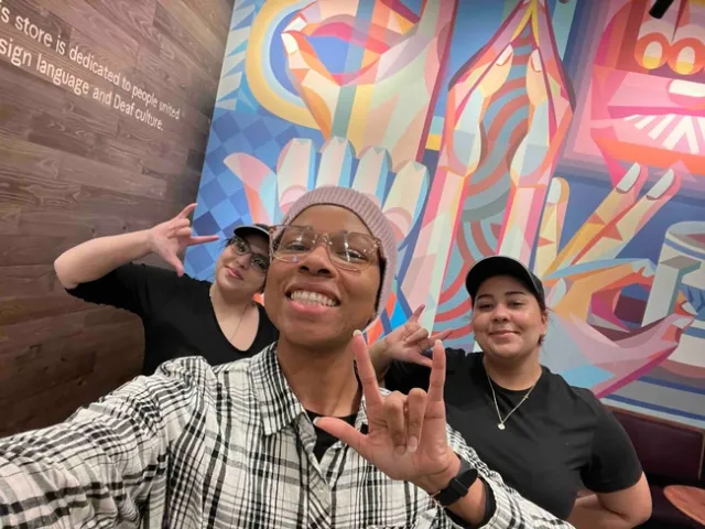 Eve in front of 2 Starbucks employees signing ILY