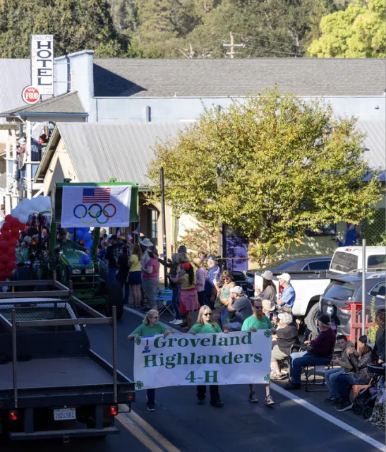 Three people in green shirts carry a banner that reads,