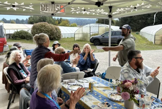 A group of people under an awning, clapping.