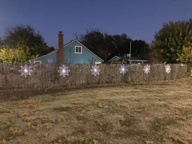 6 white plastic hanger snowflakes on a fence with white led lights