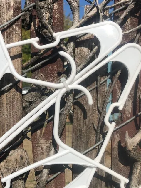 Close-up of portions of 4 white plastic hangers and a connecting clear zip tie