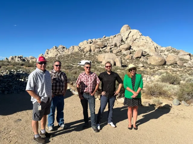 A group of people stand in front of rock formations in the Eastern Sierra