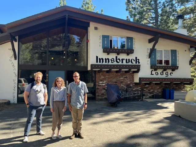 Three people pose and smile for a photo in front of a former lodge property