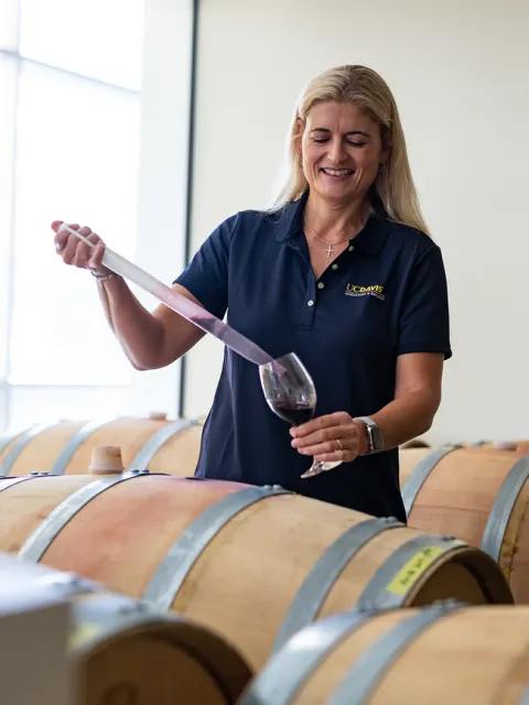 Anita Oberholster, a professor of Cooperative Extension in the Department of Viticulture and Enology, extracting wine from casks in the Teaching and Research Winery. (Jael Mackendorf / UC Davis)